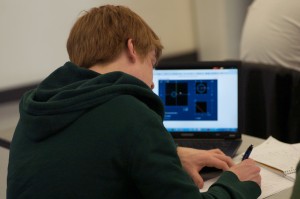 Photo of student working on homework with Mathlet in background